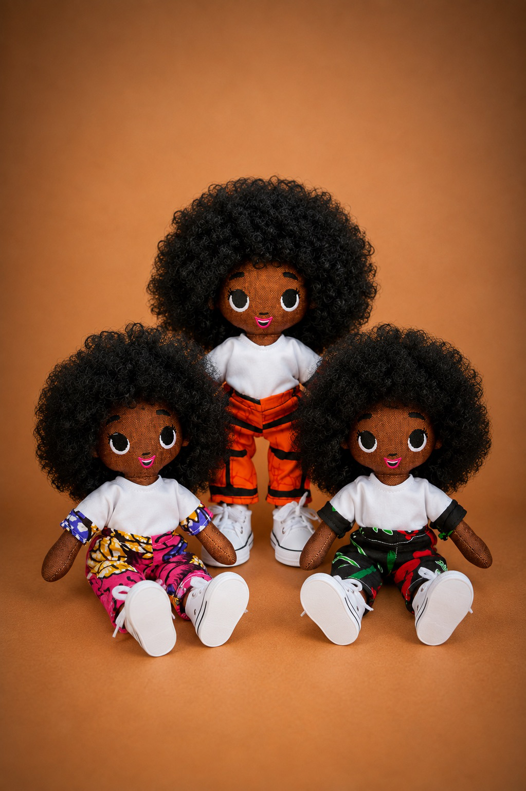Three Tara dolls wearing colorful African-print outfits